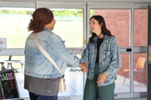 A woman shakes hands with another woman.